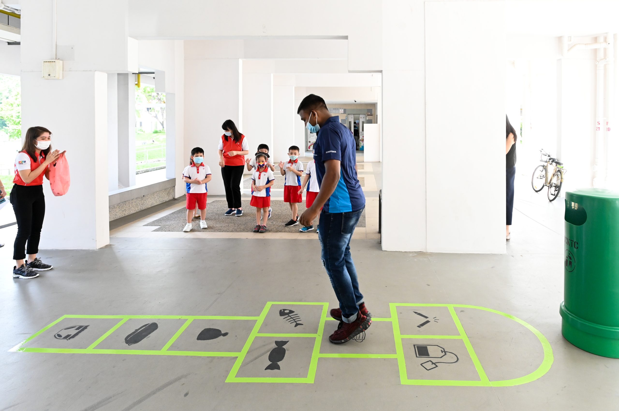Uncle Nonyo learning to play hopscotch with the children cheering on.