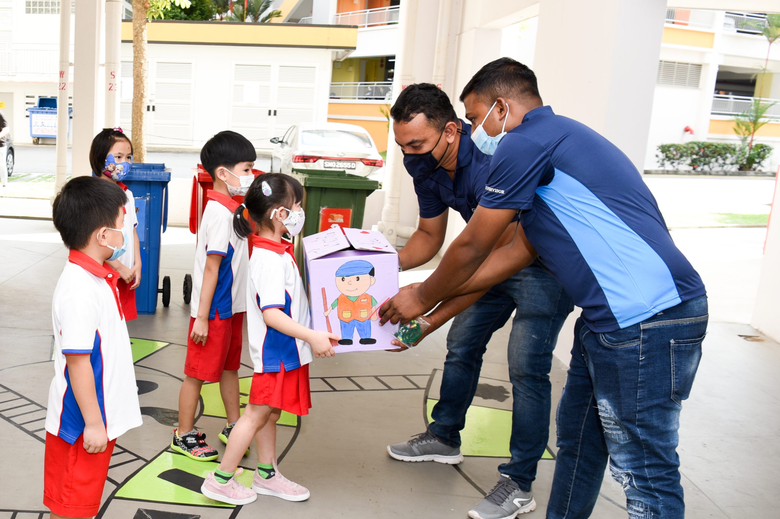 Yue Qiao Tong Phoebe presenting a box of 70 handmade mask lanyards for all the town’s cleaners to Uncles Islam (in black mask) and Nonyo to thank them for their work. Behind her (from left) are Chean Wei Xian, Fang Jiamin Jolene and Leo How Bo Ren.