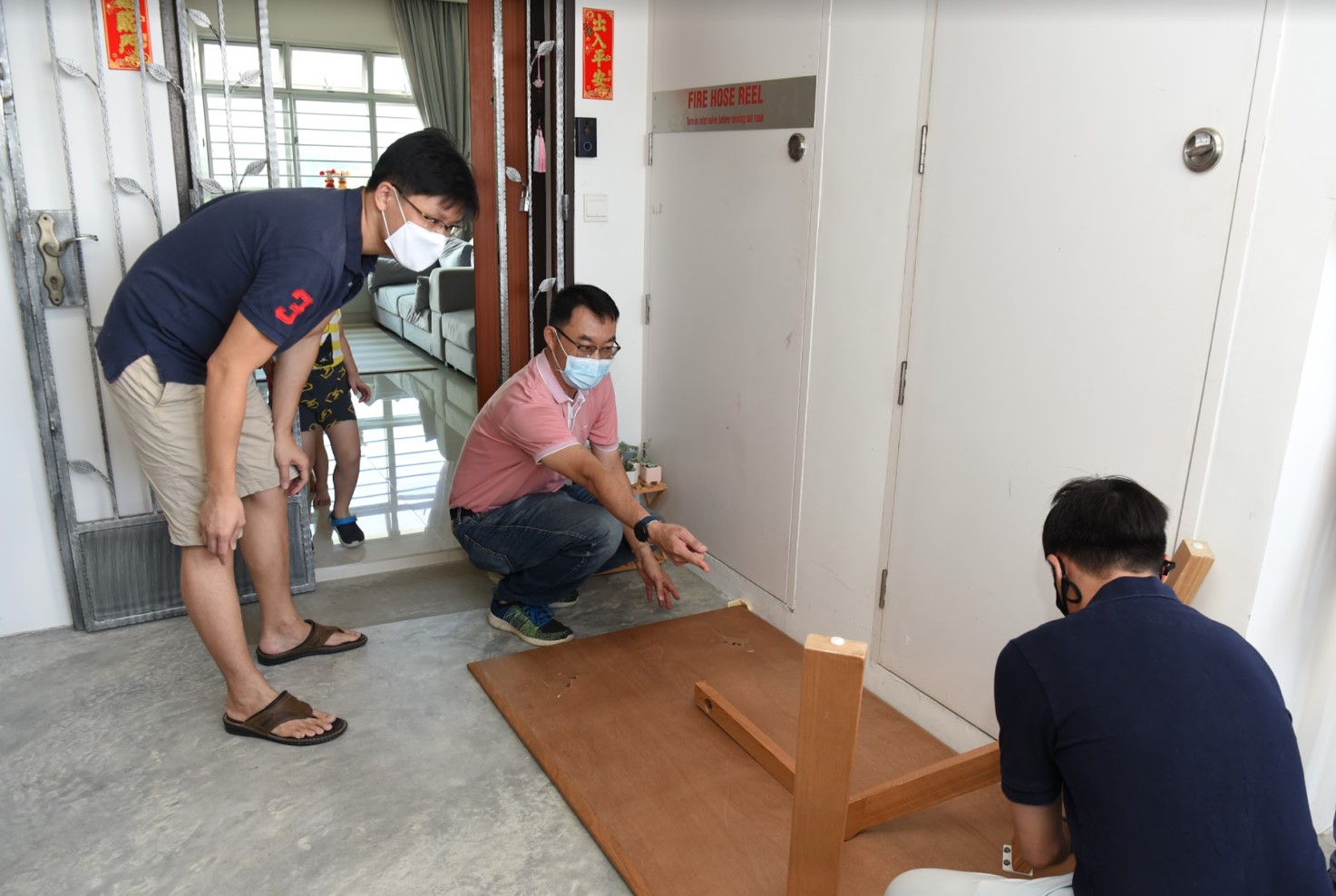 Resident Leow Geng Hui (standing, on left) looking on as volunteers prepare to transport his dining table.